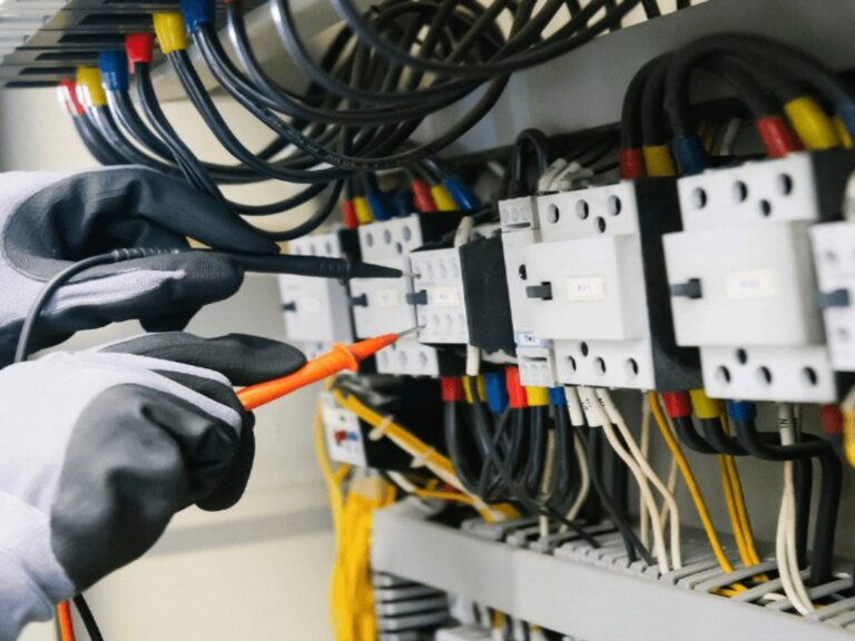 Elettricista Sassari al lavoro su un quadro elettrico con il tester